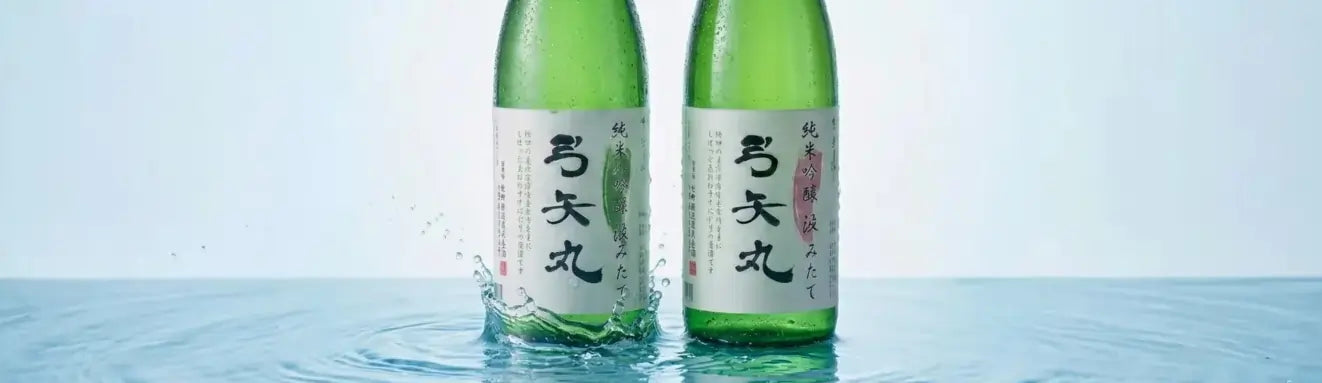 Two green sake bottles with labels on a blue water background