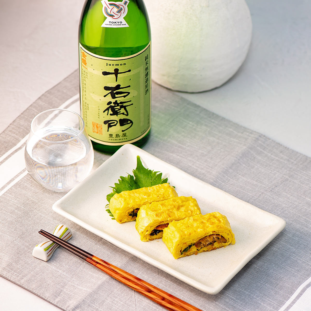 Juemon “Junmai,” with a sake glass, served with “Umaki” (a rolled, glazed eel omelet).