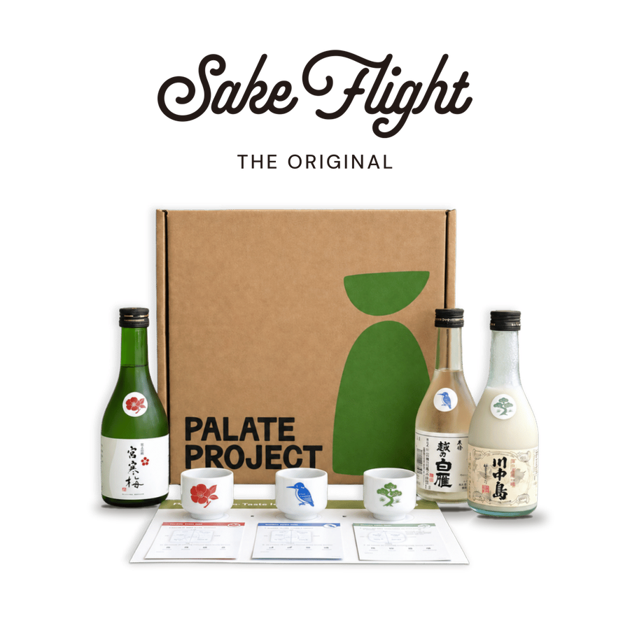The Sake Flight logo above the gift box, three mini-bottles, three cups and a tasting mat