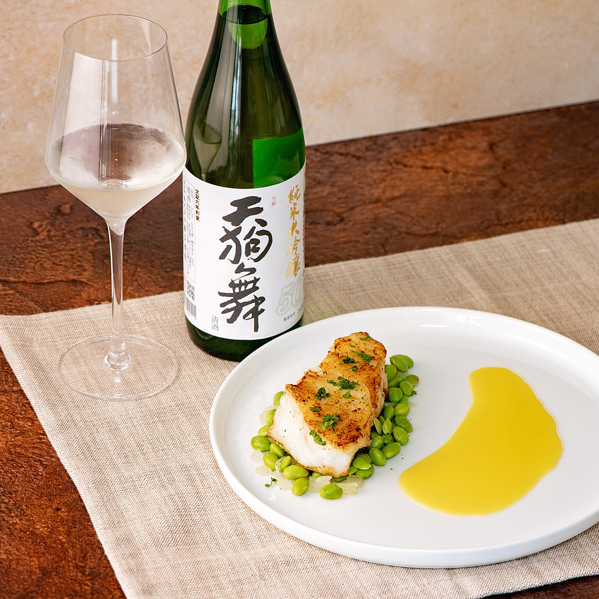 Tengumai “50,” with a wine glass, served with a pan seared Chilean sea bass with edamame, onion and beurre blanc